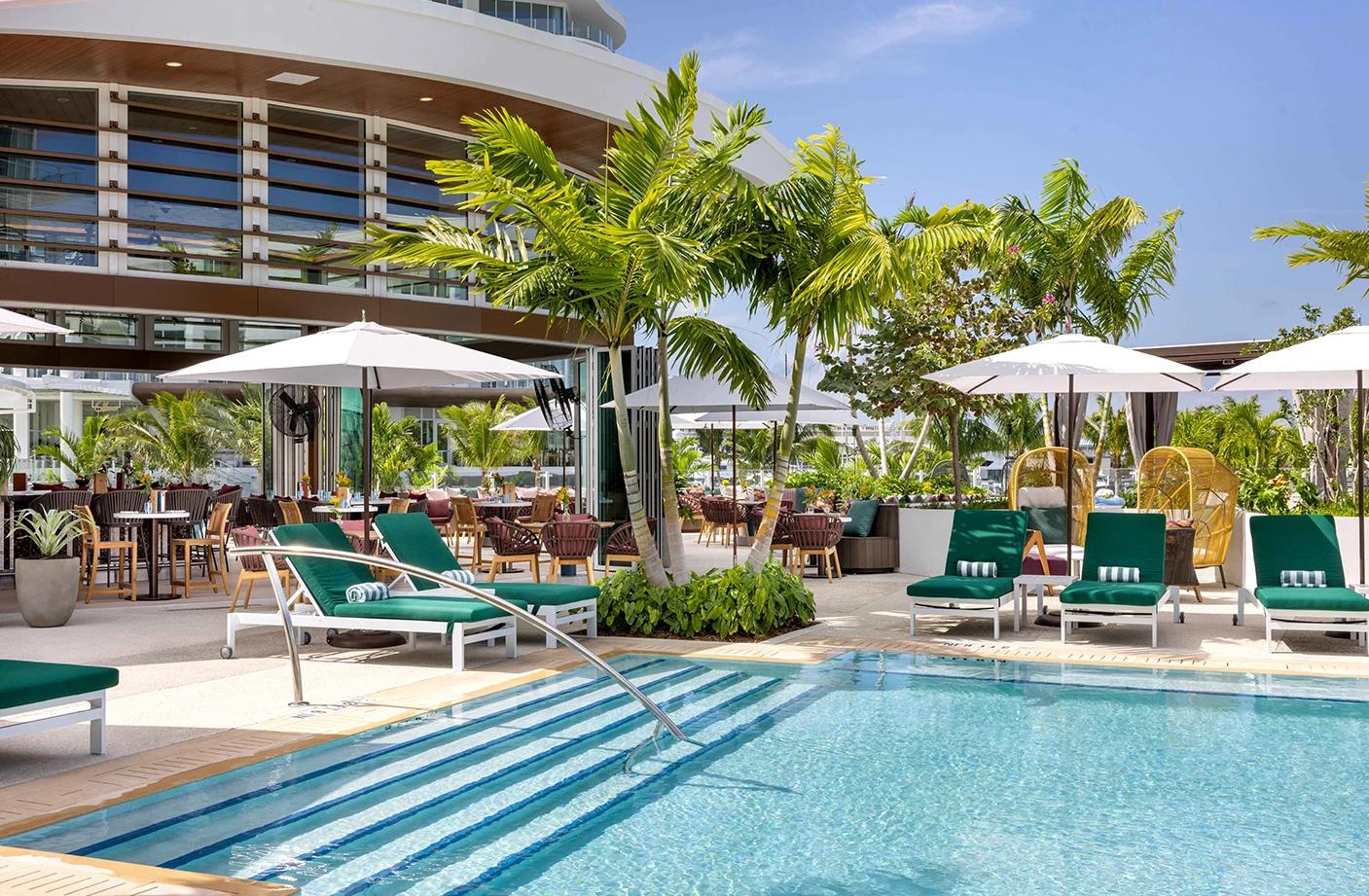 a pool with chairs and umbrellas by a building