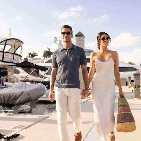 a man and woman holding hands and walking on a dock