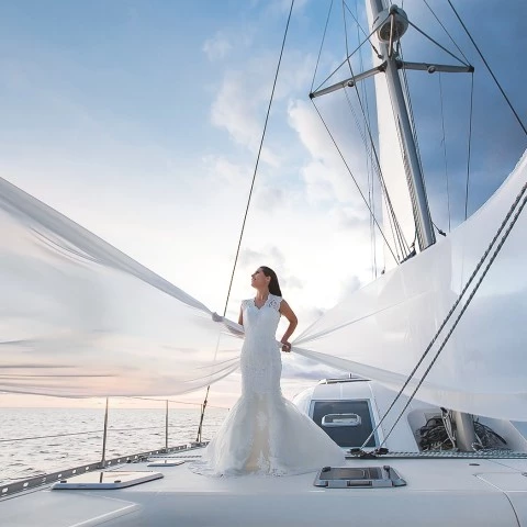 a man in a white dress standing on a boat in the water