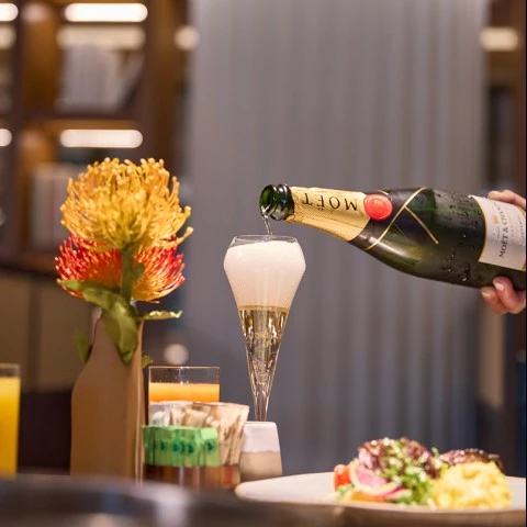 a person pouring champagne into a glass