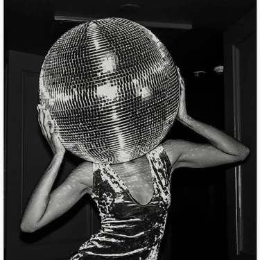 a woman holding a disco ball over her head
