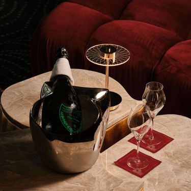 a wine bottle in a bucket and glasses on a table