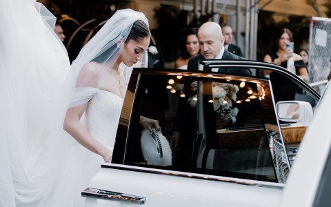 a woman in a wedding dress getting into a car