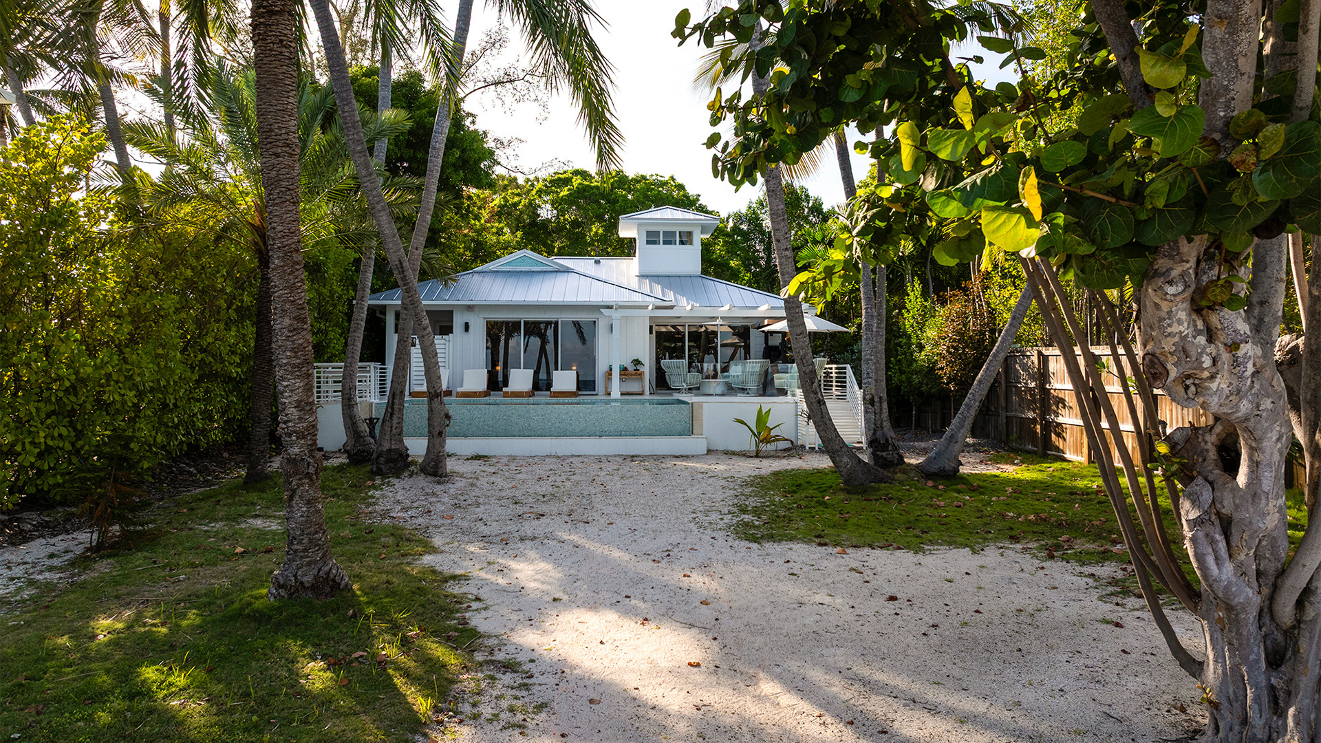 a house with a white wall and a white walkway with trees