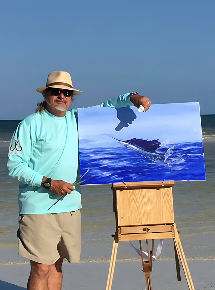 a man holding a painting on a beach