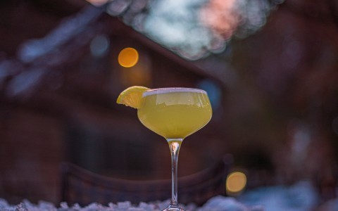 a glass of yellow liquid with a slice of lemon on top