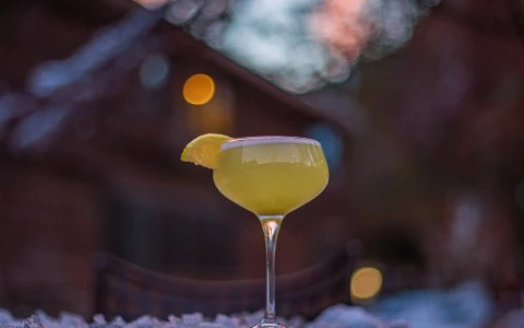 a glass of yellow liquid with a slice of lemon on top