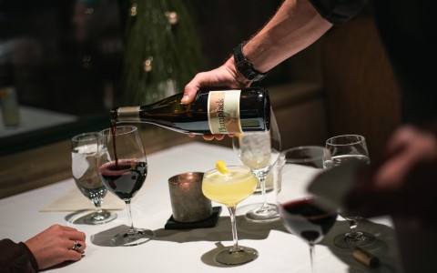 a person pouring wine into glasses