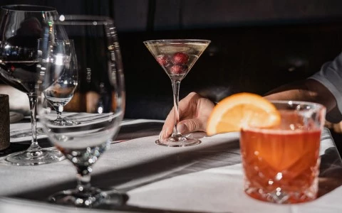 a hand holding a martini glass with berries in it