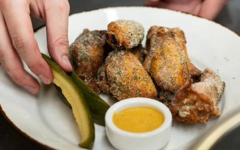 a plate of fried chicken wings and a pickle