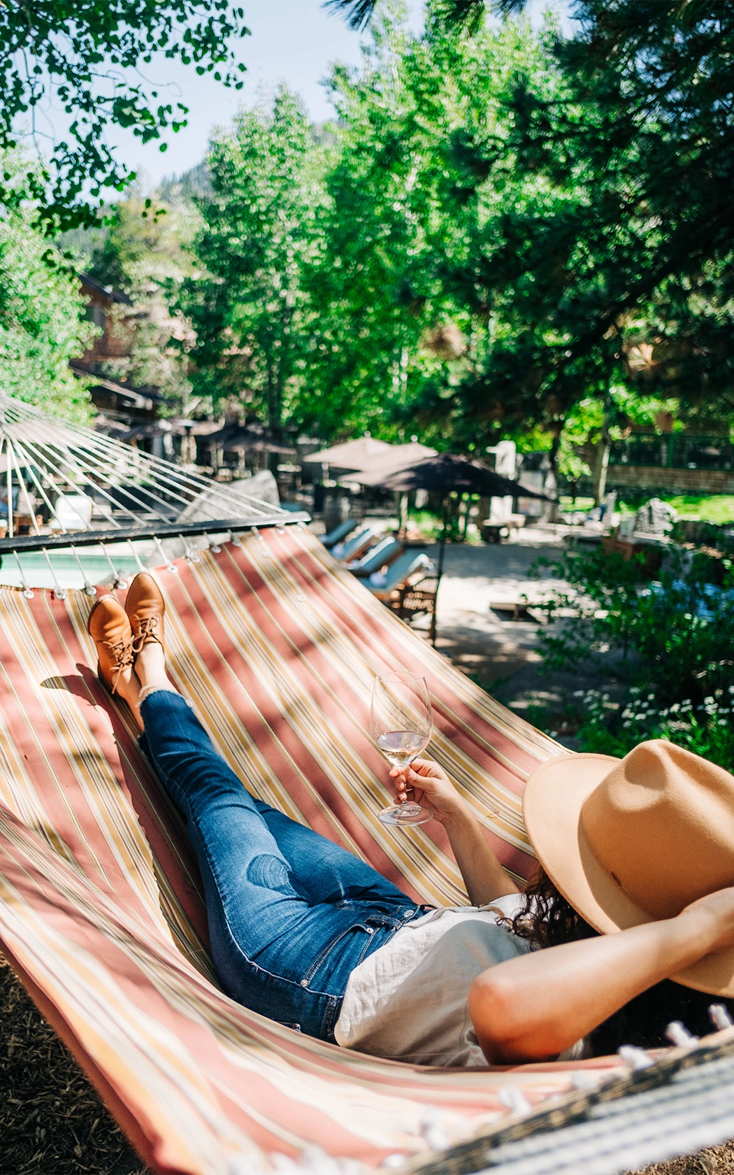 a woman lying in a hammock with a glass of wine