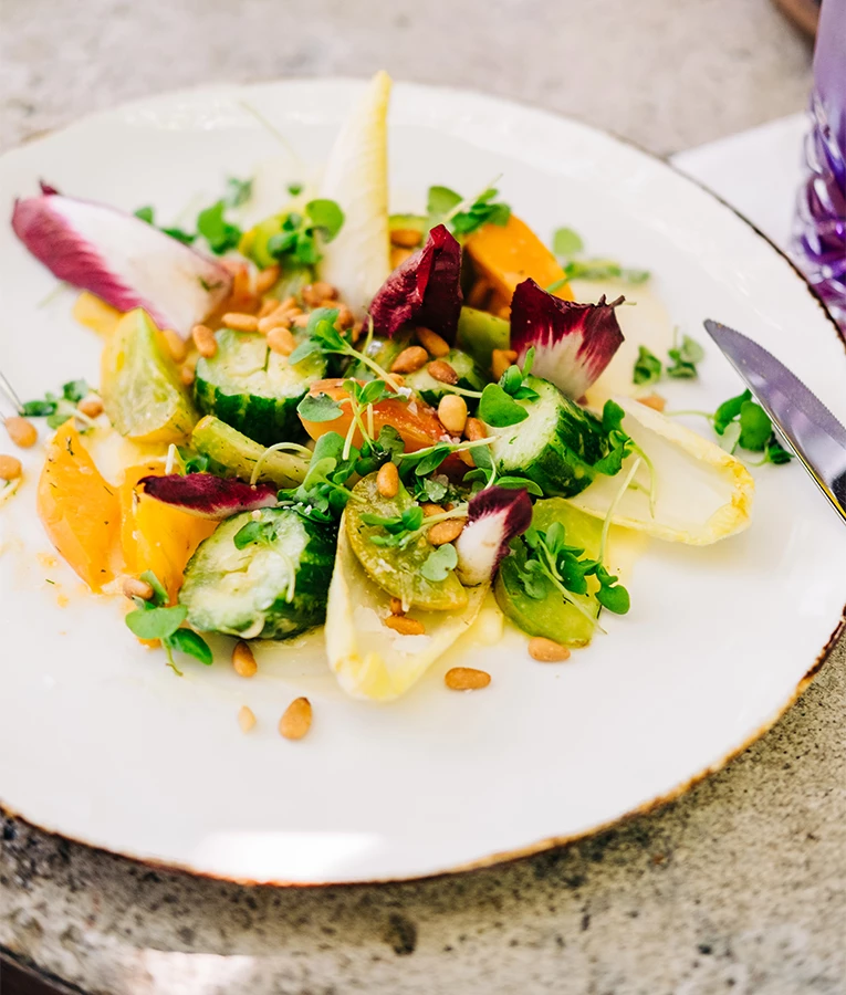 a plate of salad with vegetables and nuts