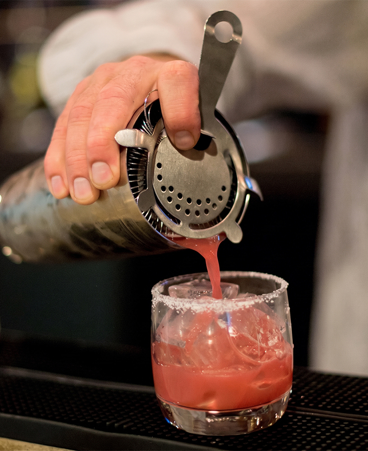 a person pouring a drink into a glass