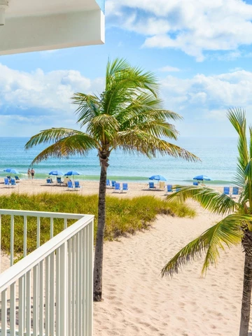 a beach with palm trees and blue umbrellas