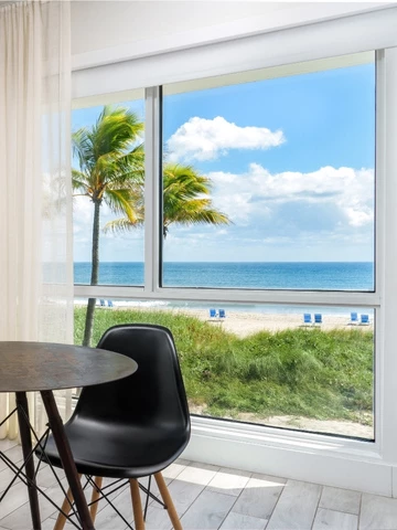 a room with a table and chairs and a beach view