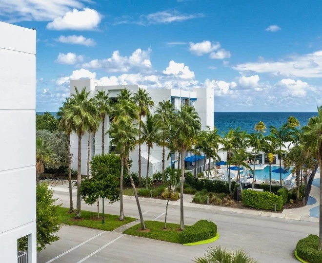 a building with palm trees and a pool in the background