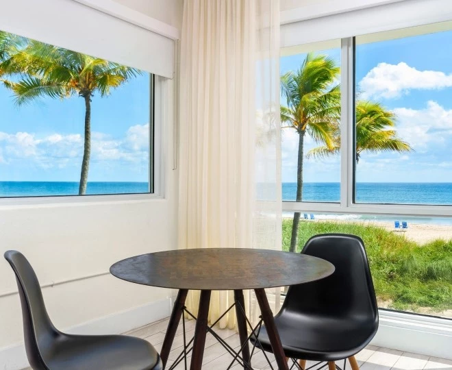 a table and chairs in a room with a view of the ocean