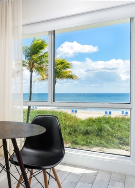 a room with a table and chairs and a beach view
