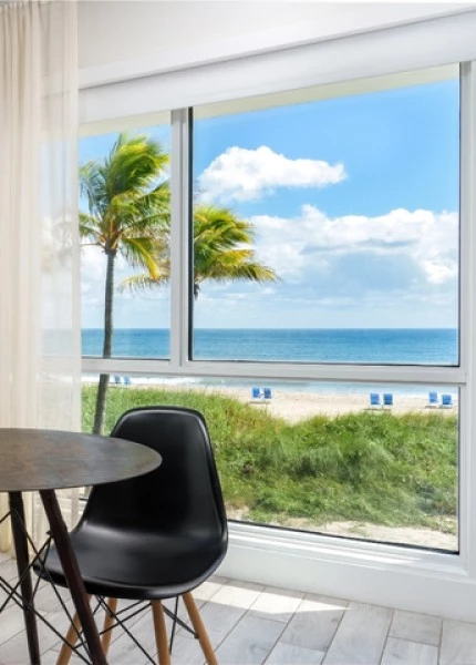 a room with a table and chairs and a beach view