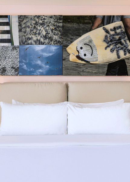 a bed with white pillows and a surfboard on the wall