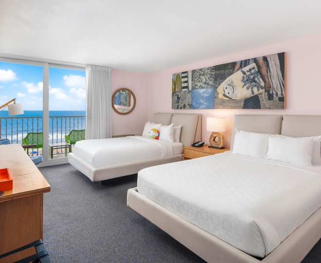 A hotel room with two beds, a balcony, and an ocean view.