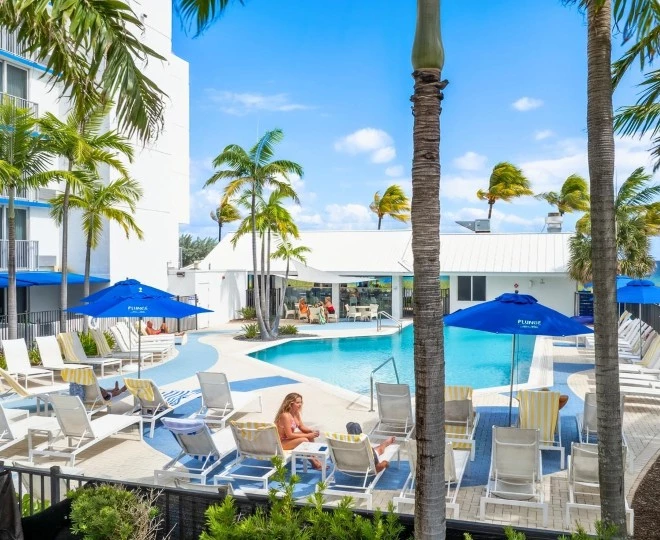 a pool with palm trees and people sitting on chairs