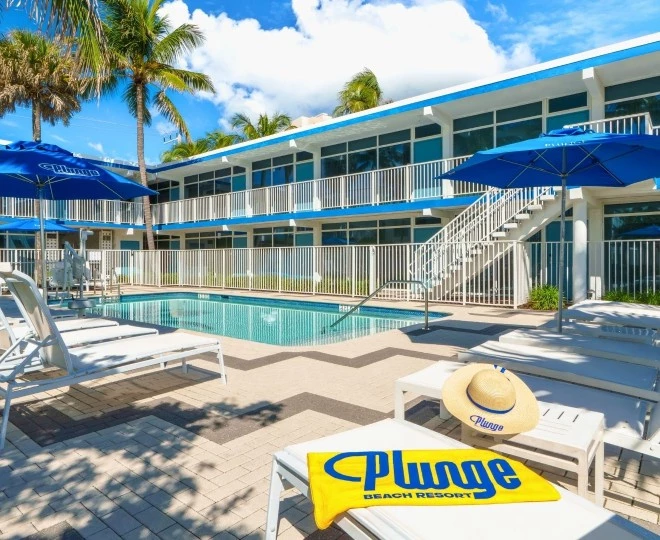 a pool with umbrellas and chairs in front of a building