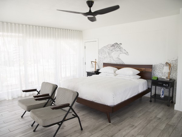 A wide view of a guest room with a large bed, two nightstands, and a seating area.