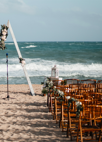 A beach setup with rows of chairs and a floral arrangement