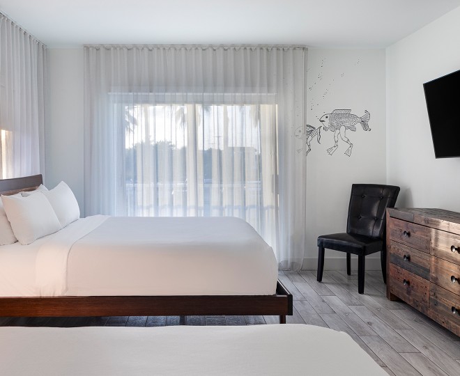 A hotel room with a large bed, window, dresser, and chair.