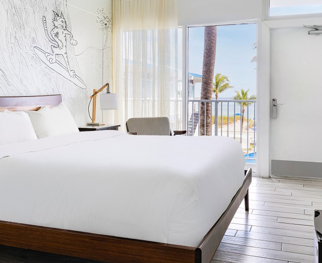 A bright and airy hotel room with a large bed, balcony, and ocean view.