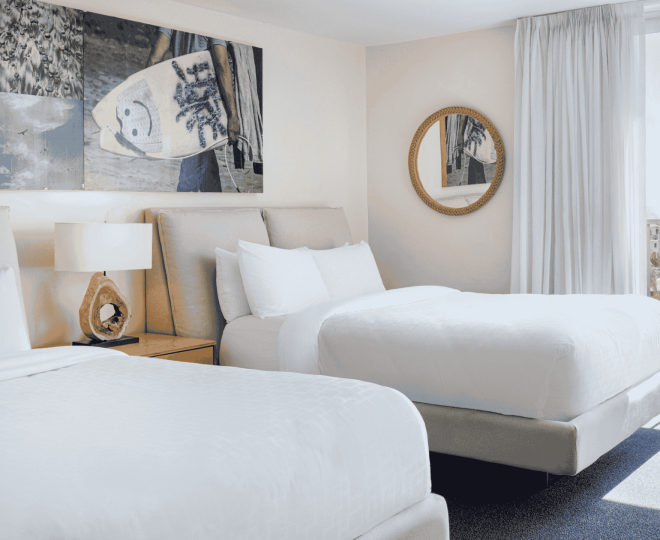 A hotel room with two twin beds, a nightstand, and a large mirror.