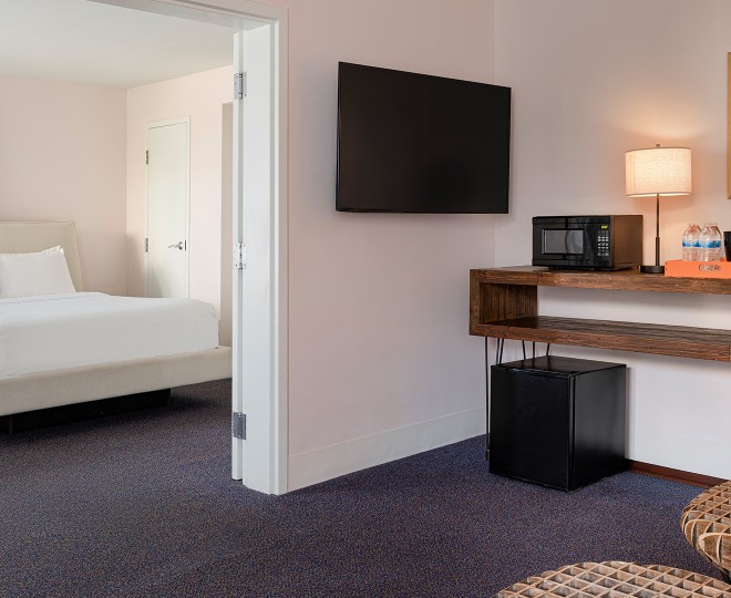 A hotel room with a bed, TV, microwave, and mini-fridge.