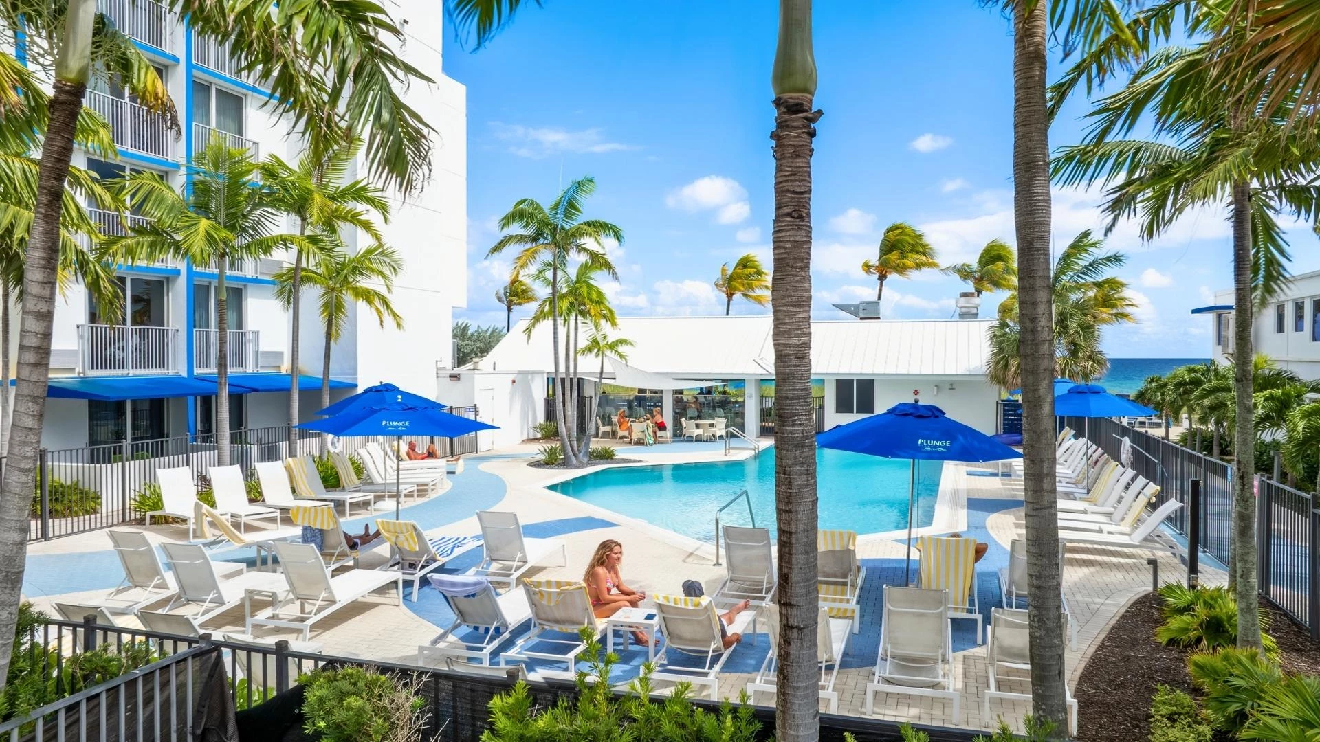 a pool with palm trees and people sitting on chairs