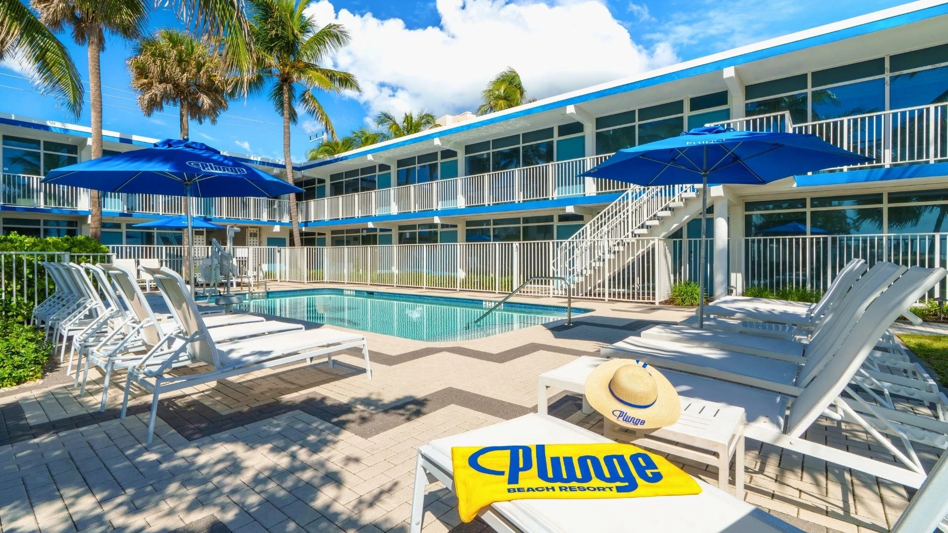 a pool with umbrellas and chairs in front of a building