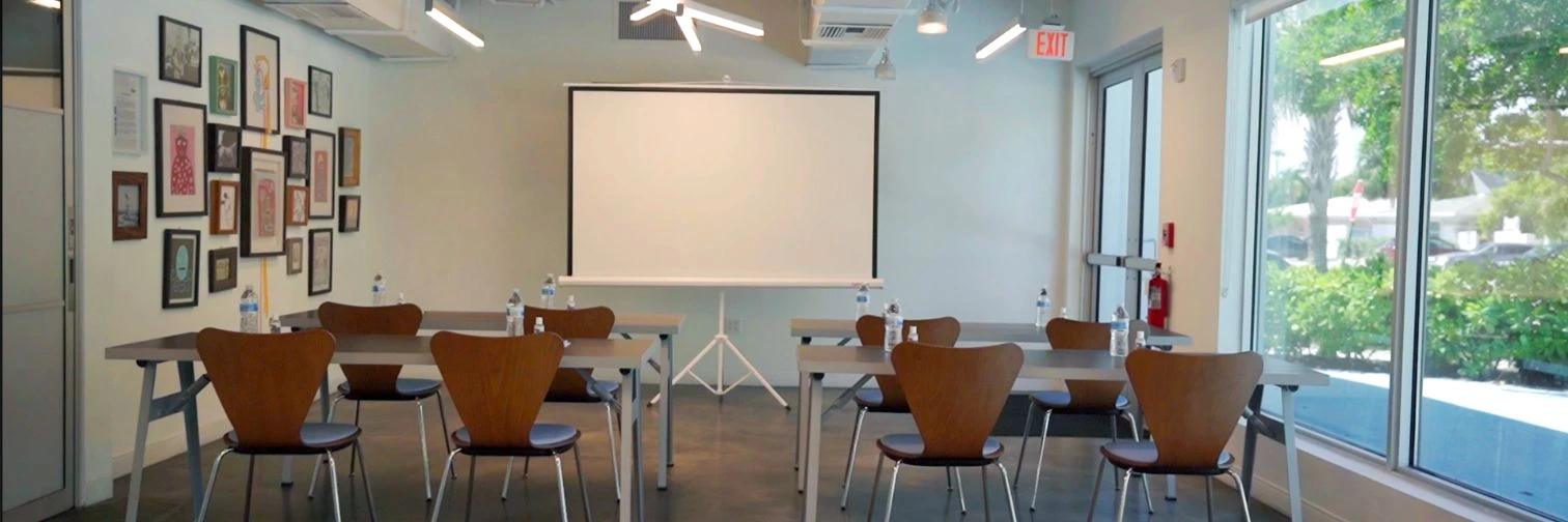a room with tables and chairs and a projector screen