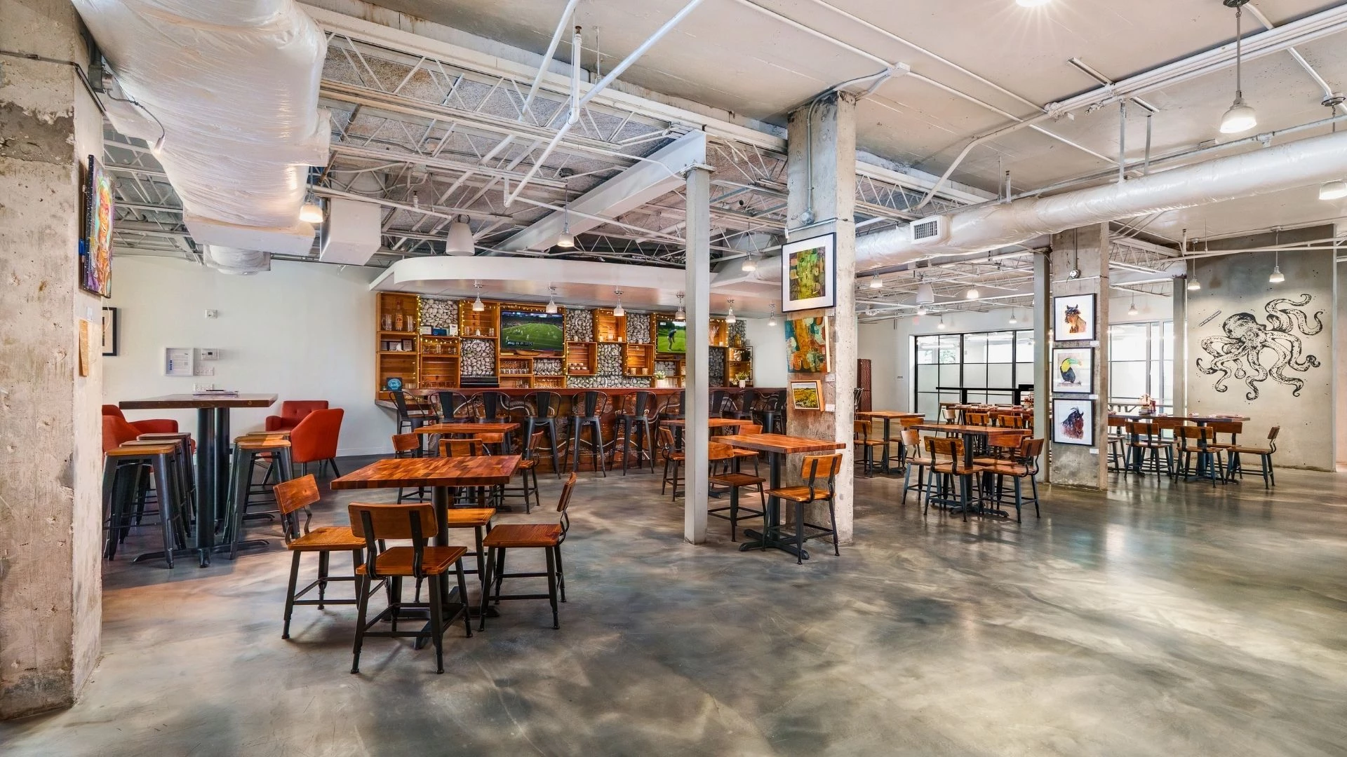 A large dining area with tables and chairs, a bar in the background, and artwork on the walls.