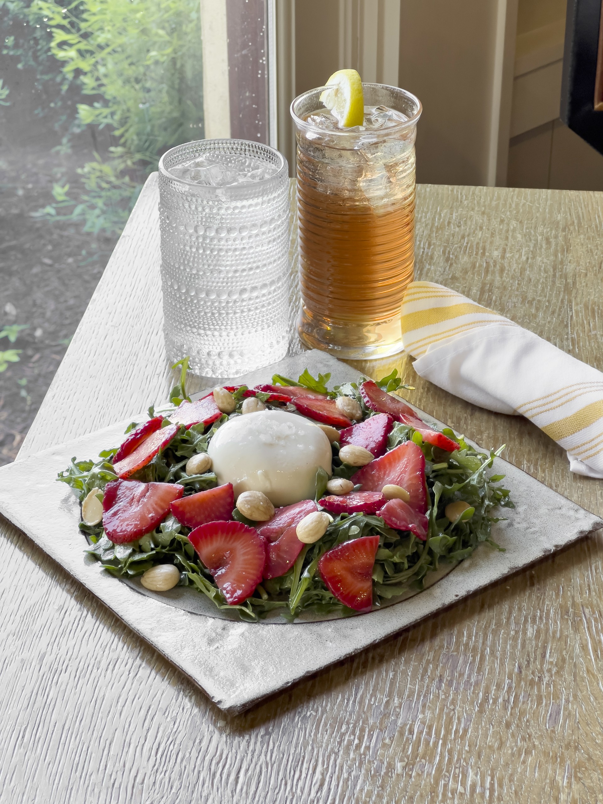 a plate of salad with strawberries and nuts on a table