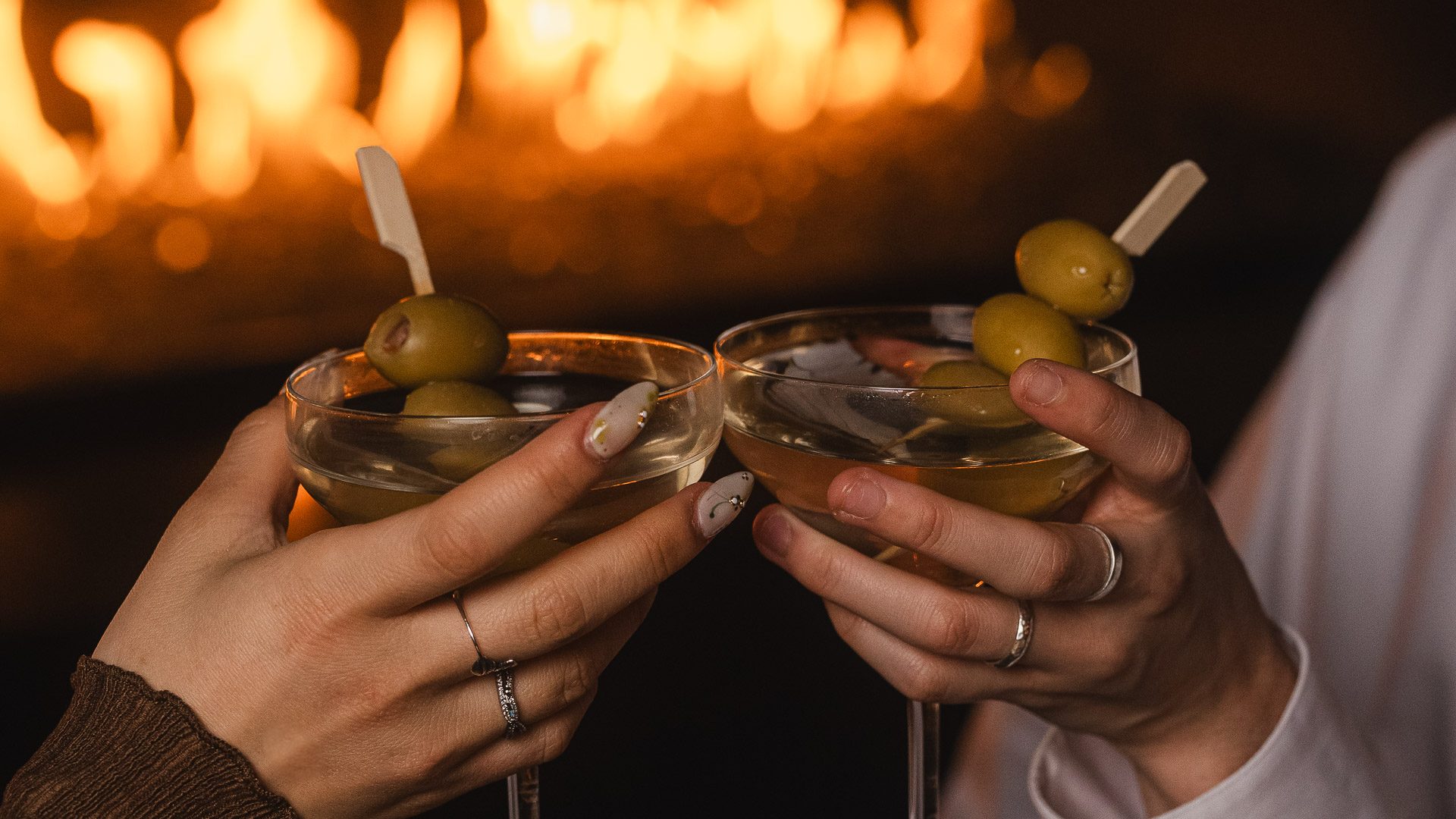 a pair of hands holding glasses with olives