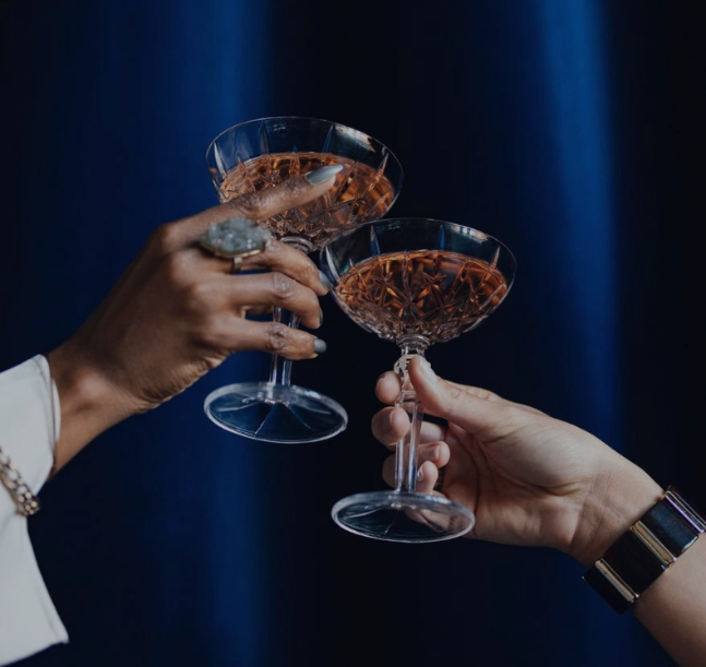 a pair of hands holding wine glasses