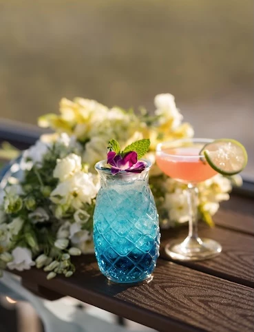 a glass with a drink and a bouquet of flowers previus