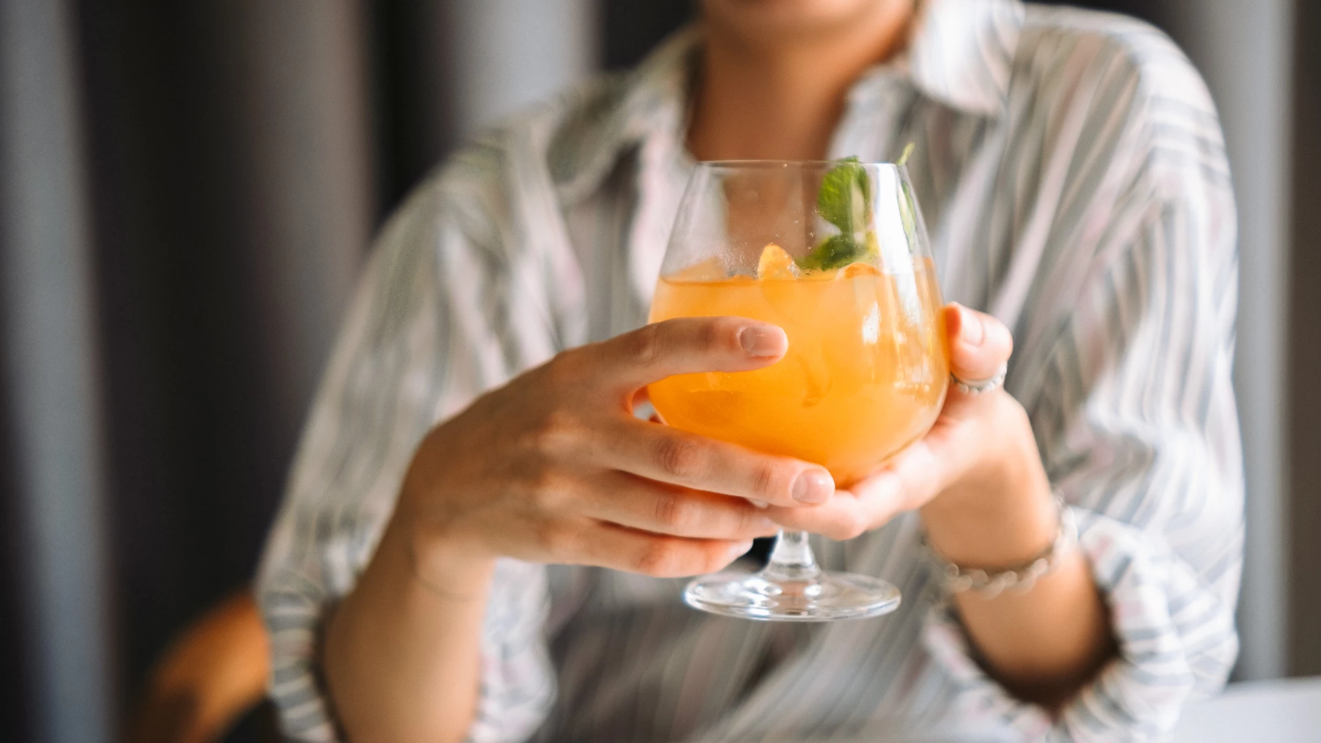 a person holding a glass of orange liquid