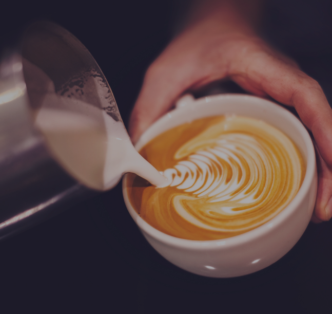 a person pouring milk into a cup of coffee