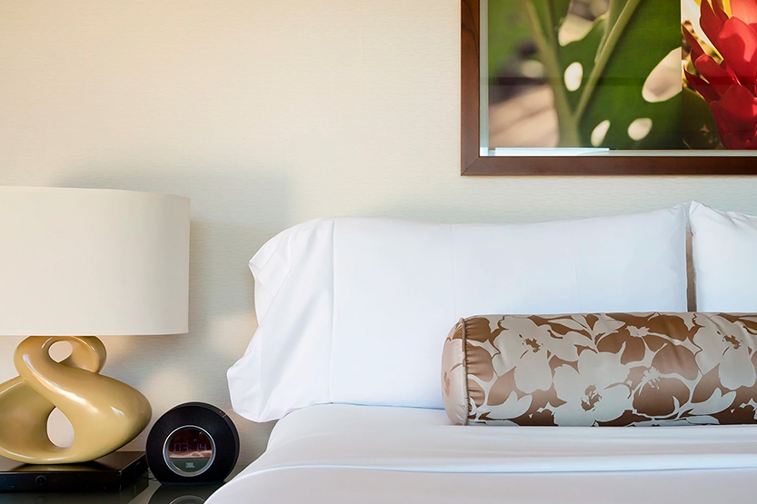 a bed with a white sheet and a brown pillow