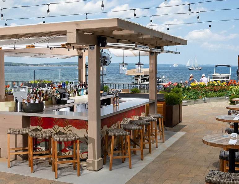 a bar with chairs and a table with a view of the water