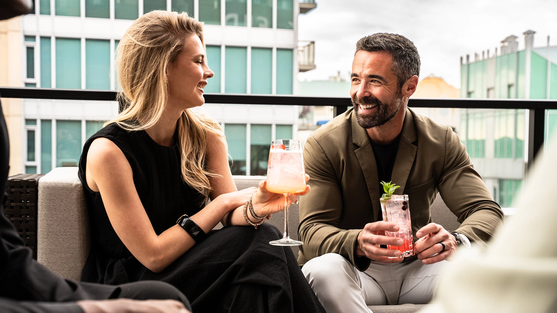a man and woman sitting on a balcony holding drinks