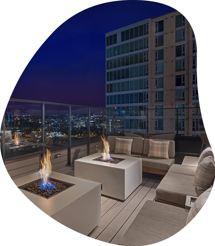 a fire pit on a deck with a large building in the background