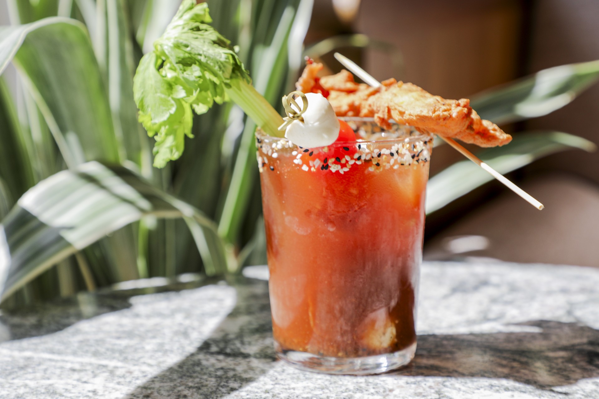a glass of bloody mary with a celery and chicken on it