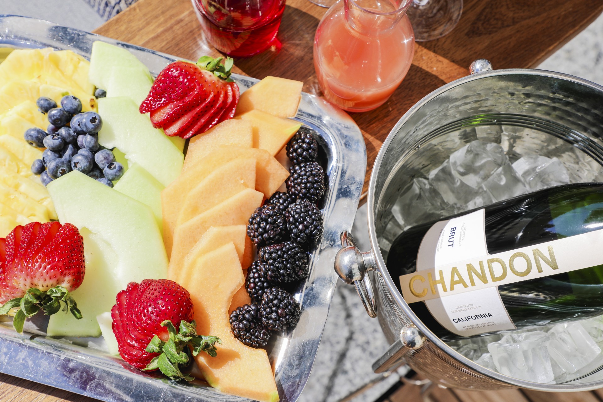 a plate of fruit and a bottle of wine next to a bucket of ice