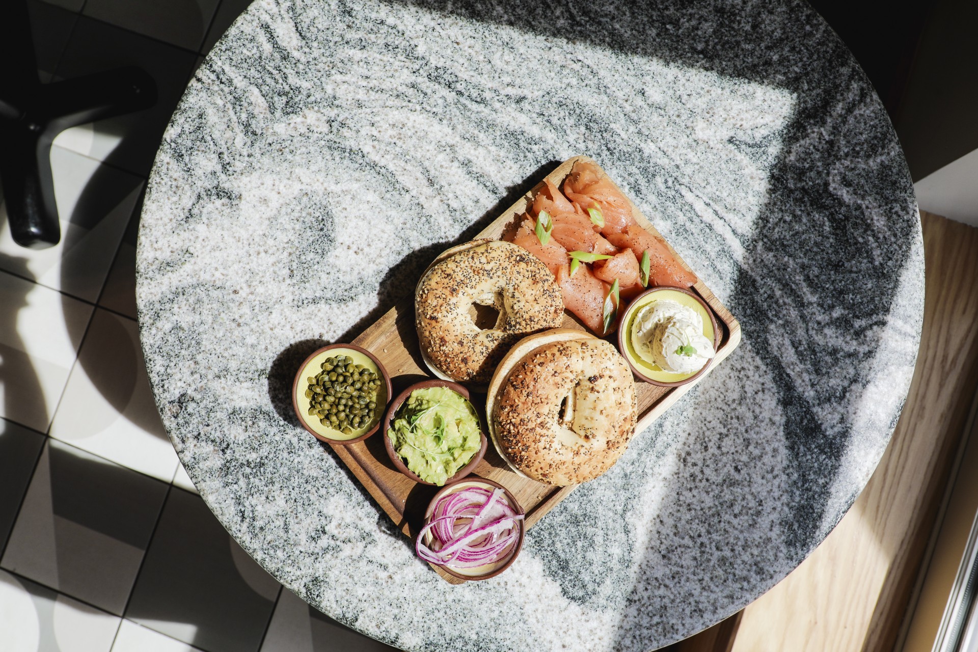 a bagel with different toppings on a wooden board